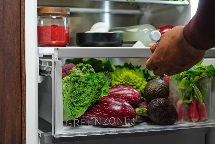 Man pulling Greenzone drawer full of vegetables inside fridge