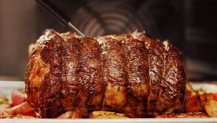 A steak with vegetables being prepared in an oven.